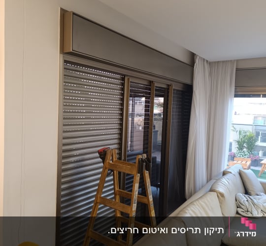 תריסים סגורים עם סולם ליד חלון בסלון